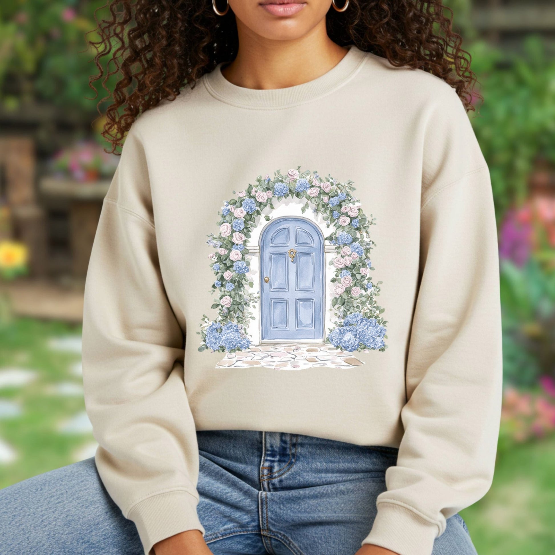 Beige sweatshirt with watercolor cottage doorway, blue door, and pink & blue hydrangeas.