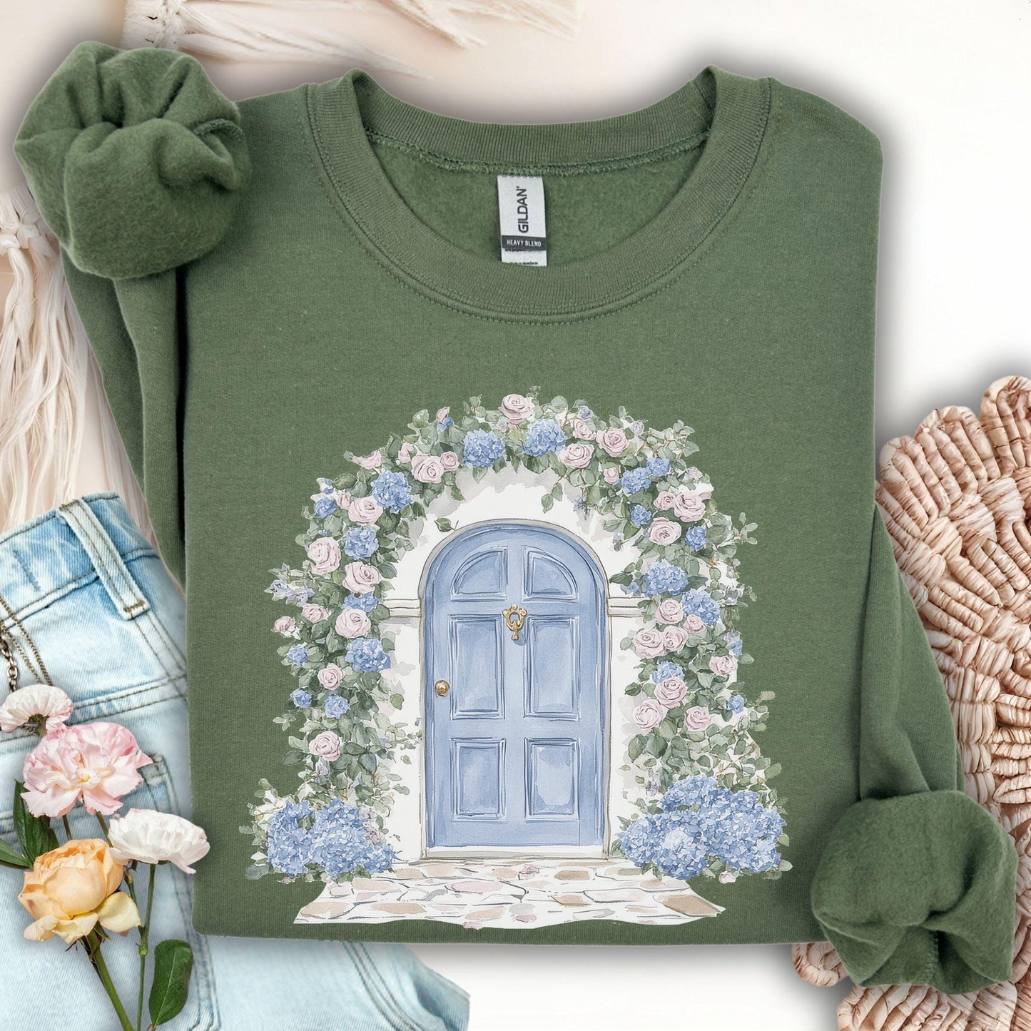 Military Green sweatshirt with a watercolor cottage doorway framed by pink roses and blue hydrangeas.