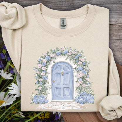 Sand sweatshirt with watercolor cottage doorway, blue door, pink roses, and blue hydrangeas.