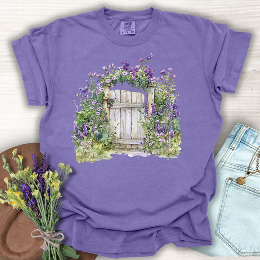 Grape S-size t-shirt with a watercolor garden gate surrounded by purple wildflowers.
