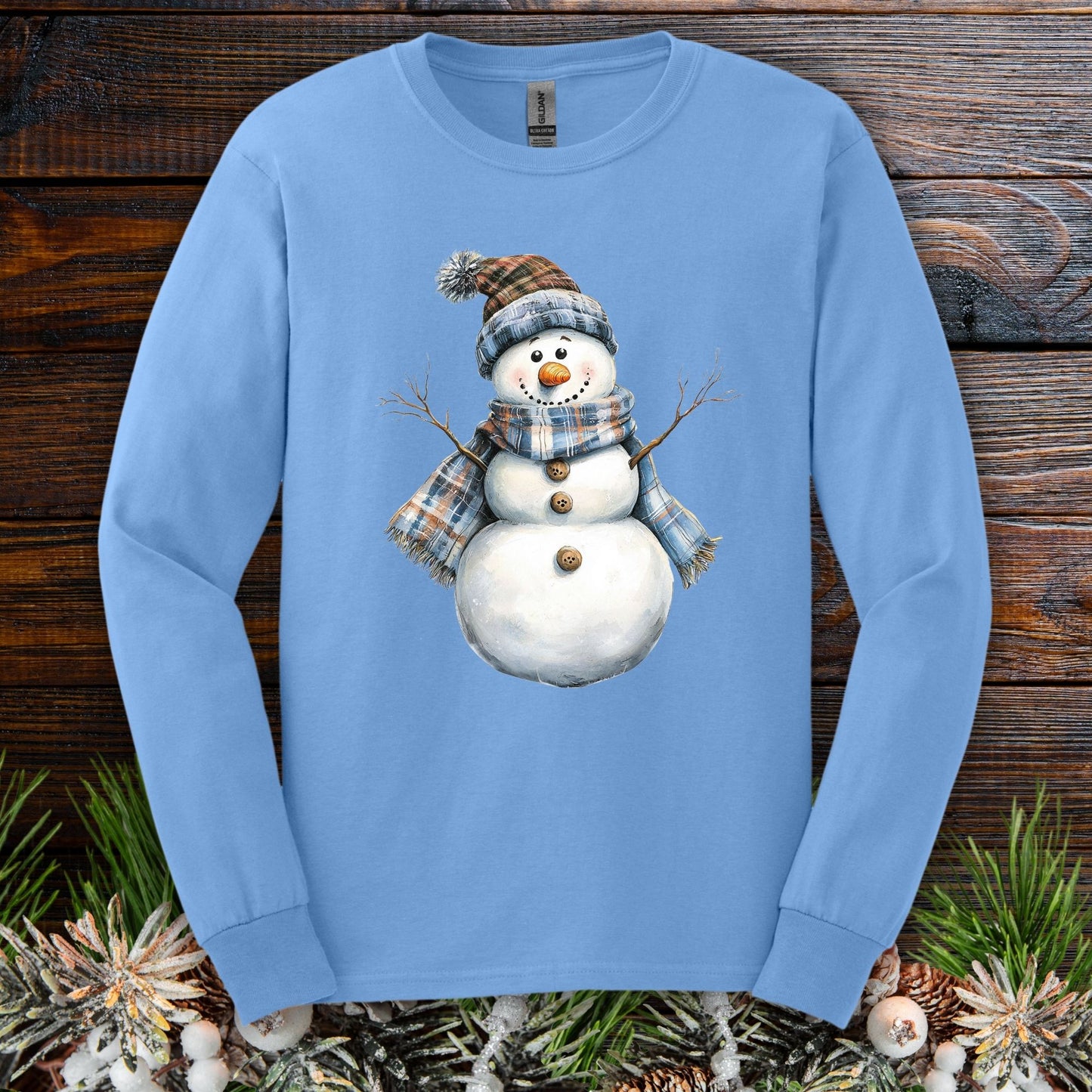 Carolina Blue long sleeve tee with a snowman wearing a blue and tan plaid hat and scarf.