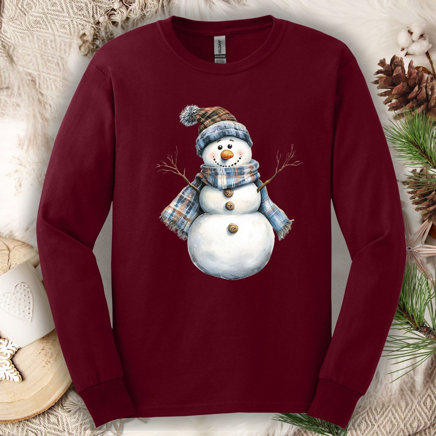 Maroon long sleeve tee with a snowman in a blue and tan plaid scarf and hat.
