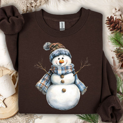 Dark Chocolate heavy blend sweatshirt with a watercolor snowman in a blue and tan plaid scarf and hat.