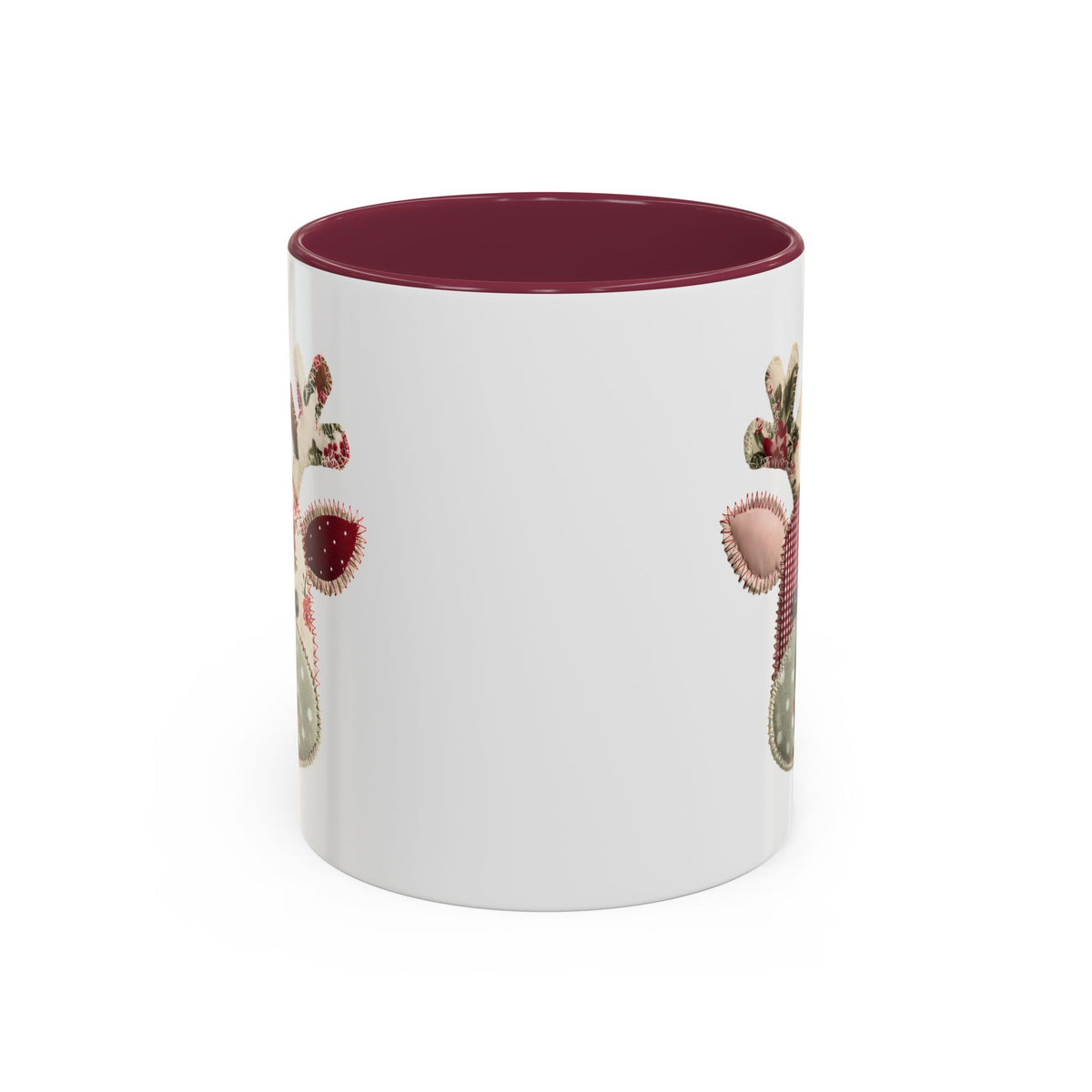 White ceramic mug with a patchwork Rudolph design, colored maroon interior, and C-shaped handle.