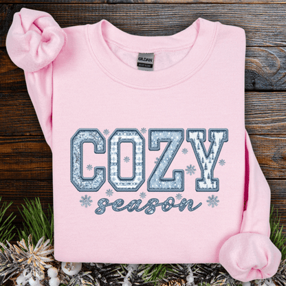 Light pink Gildan sweatshirt with "COZY season" in blue and white faux patchwork print.