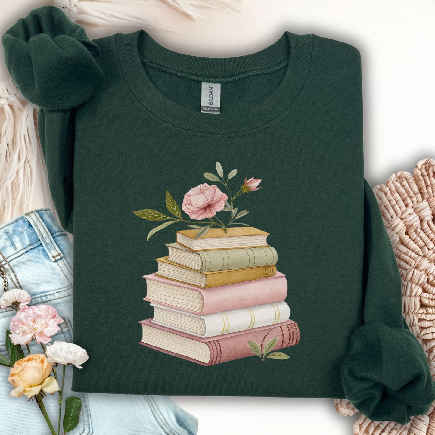 Dark green sweatshirt with a botanical illustration of stacked books and pink flowers.