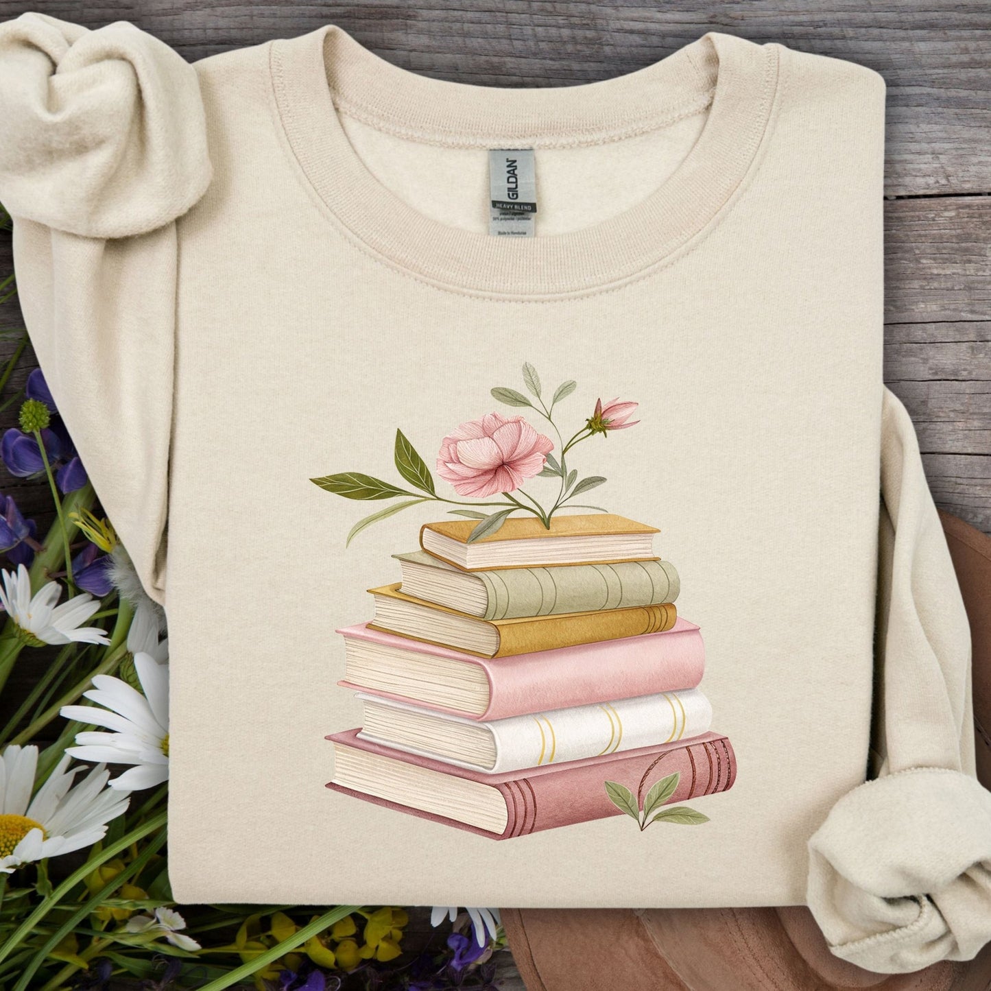 Sand sweatshirt with botanical art of stacked books and pink flowers.