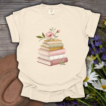 Ivory S Cozy Spring Reading T-Shirt with watercolor books and pink floral design on wood.