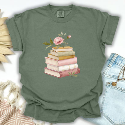 Moss green garment-dyed t-shirt with a watercolor stack of books and pink floral illustration.