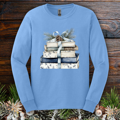 Carolina Blue long sleeve tee with a stack of blue and white books, ribbon, evergreen, and pinecone design.