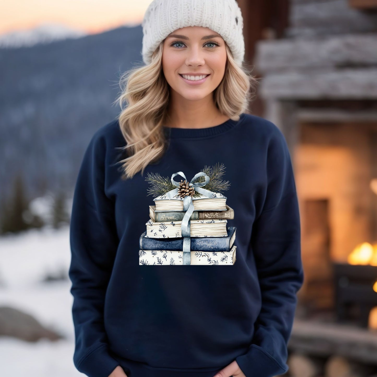 Woman in a navy sweatshirt with a stack of blue and white books, ribbon, evergreen, and pinecone design.