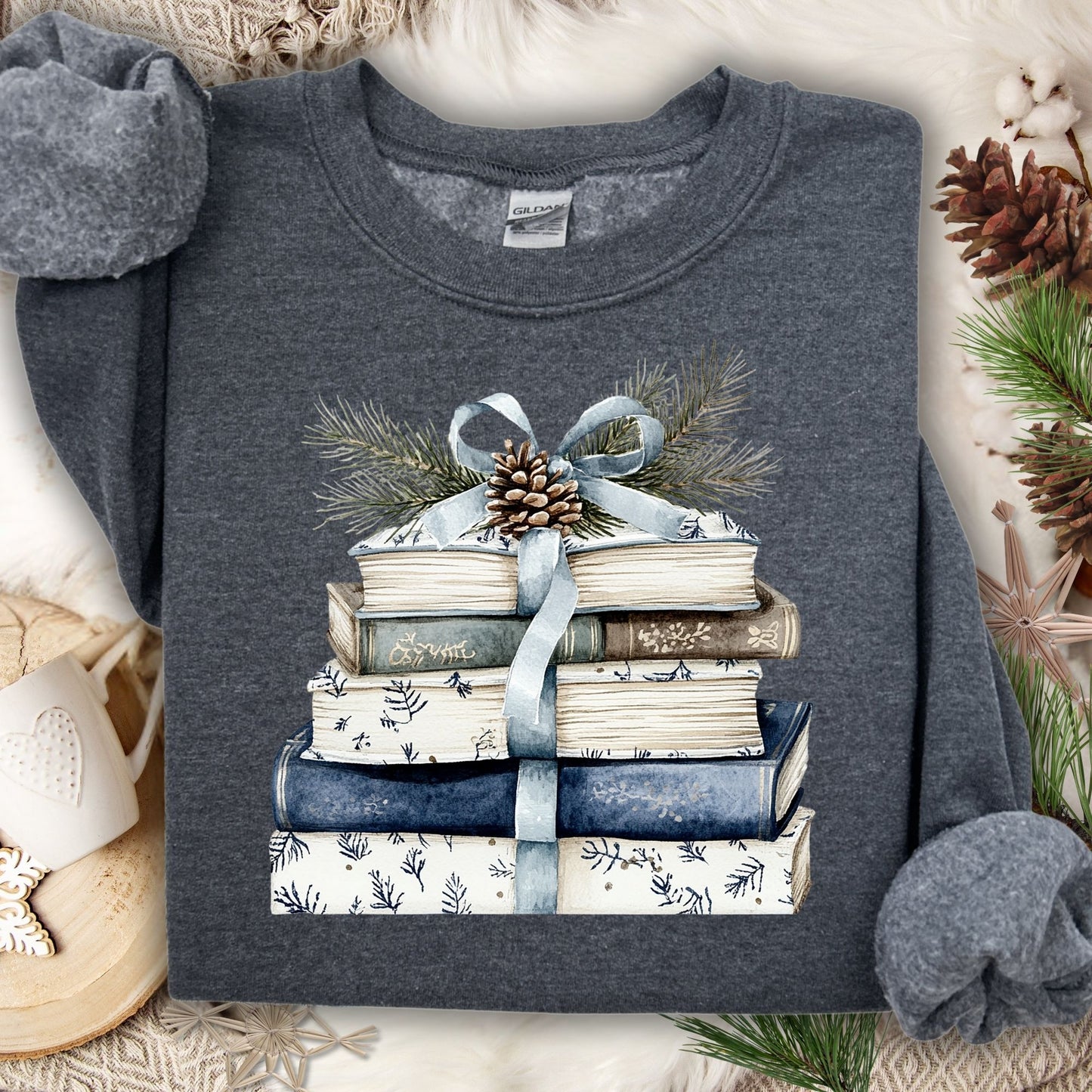 Dark Heather S sweatshirt with a stack of blue and white books, ribbon, evergreen, and pinecone design.
