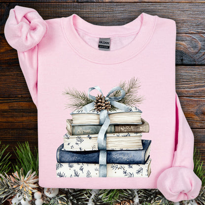 Light pink Gildan sweatshirt with a stack of blue and white books, ribbon, evergreen, and pinecone design.