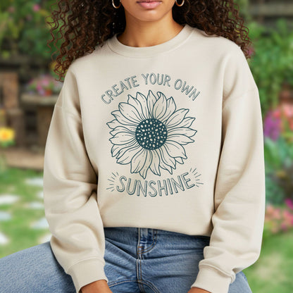 Beige unisex sweatshirt with a hand-drawn sunflower and "Create Your Own Sunshine" text.