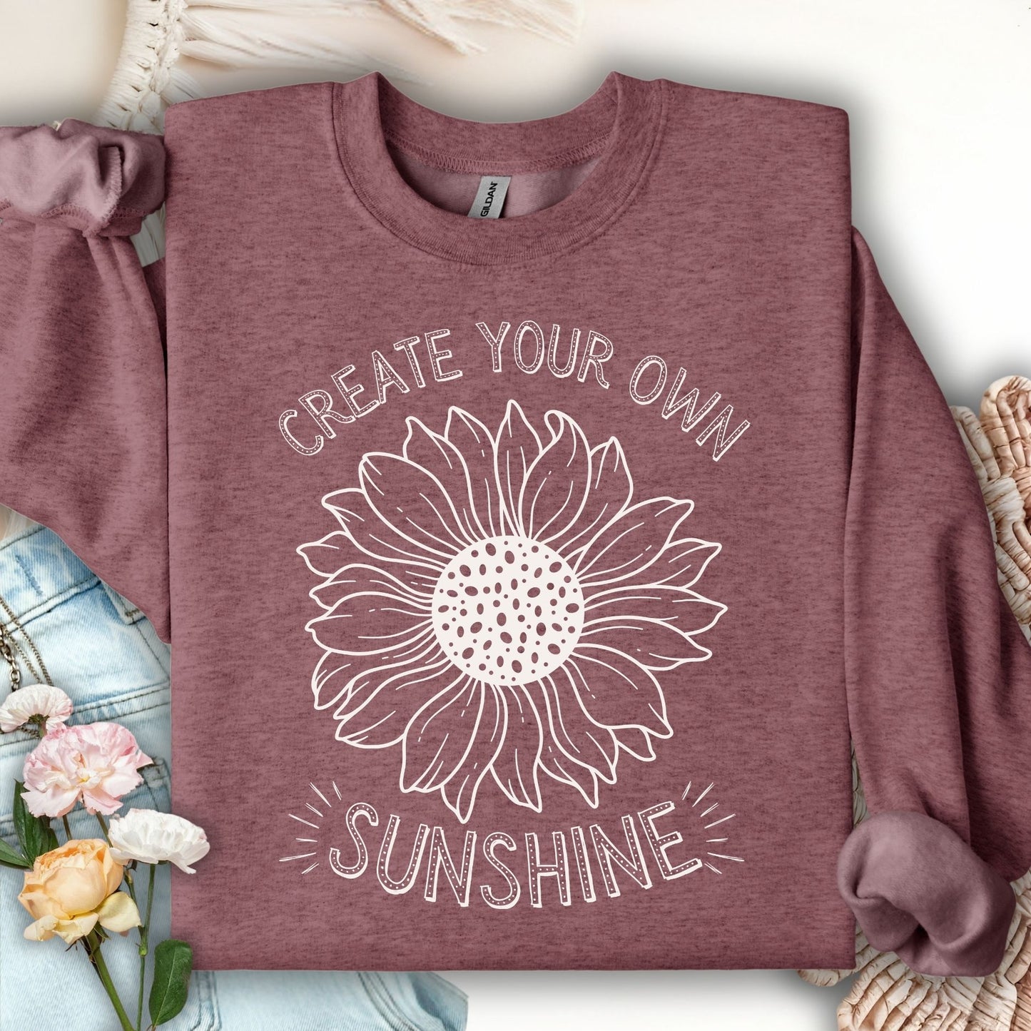 Heather Sport Dark Maroon sweatshirt with a white hand-drawn sunflower and "Create Your Own Sunshine" text.