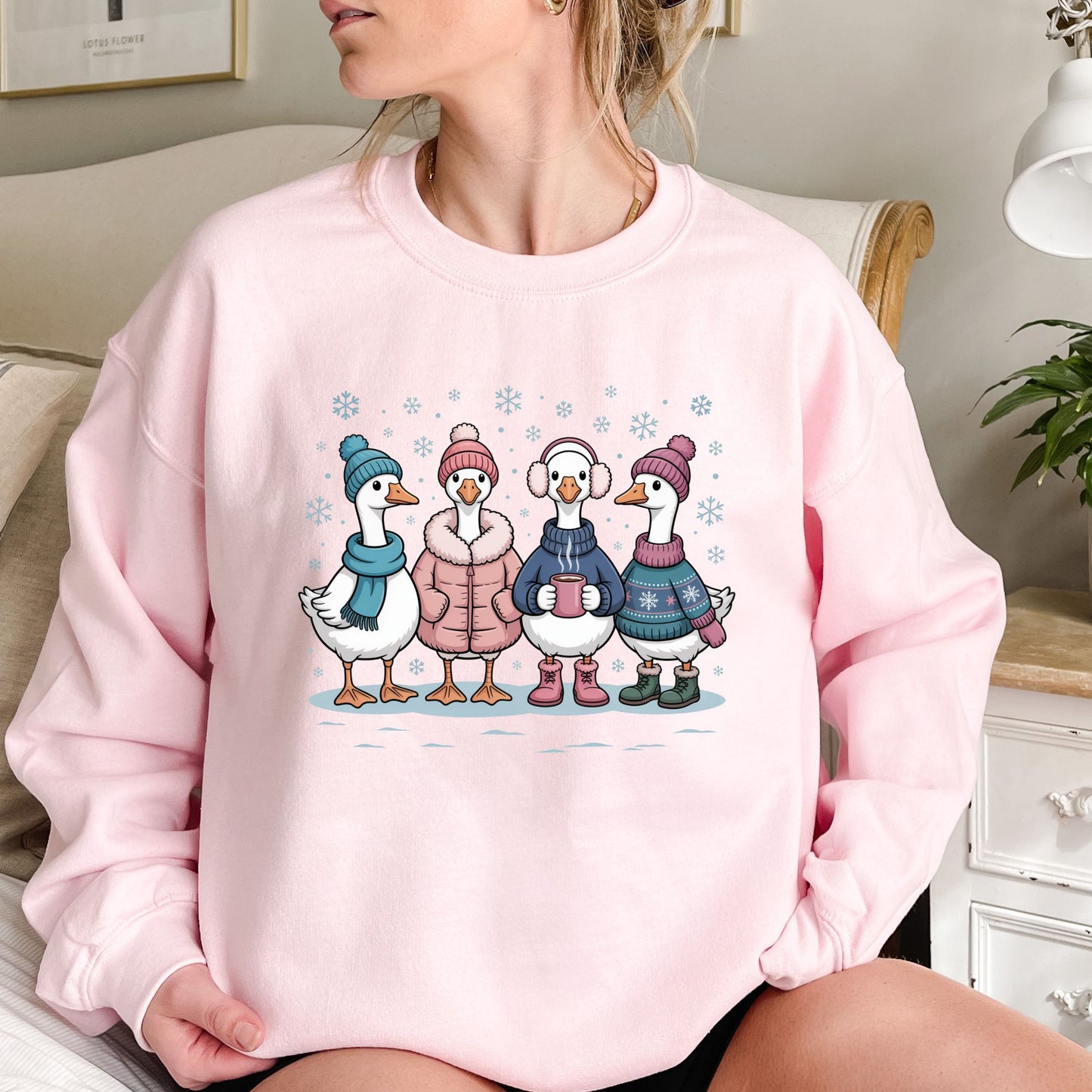 Pink cotton-polyester sweatshirt with four cartoon geese in winter hats, sweaters, and mittens, drinking hot chocolate.