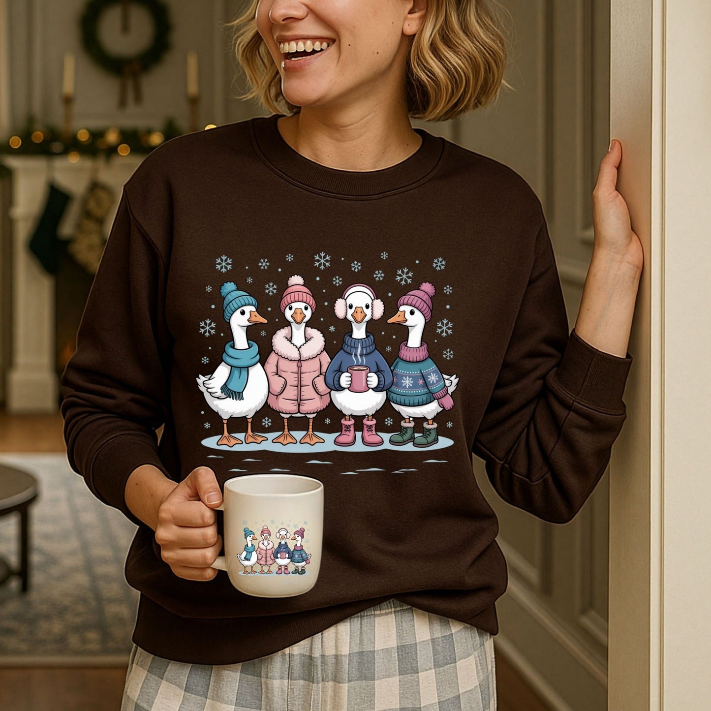 Woman in a brown winter geese sweatshirt with four geese in sweaters, hats, and mittens, holding a matching mug.
