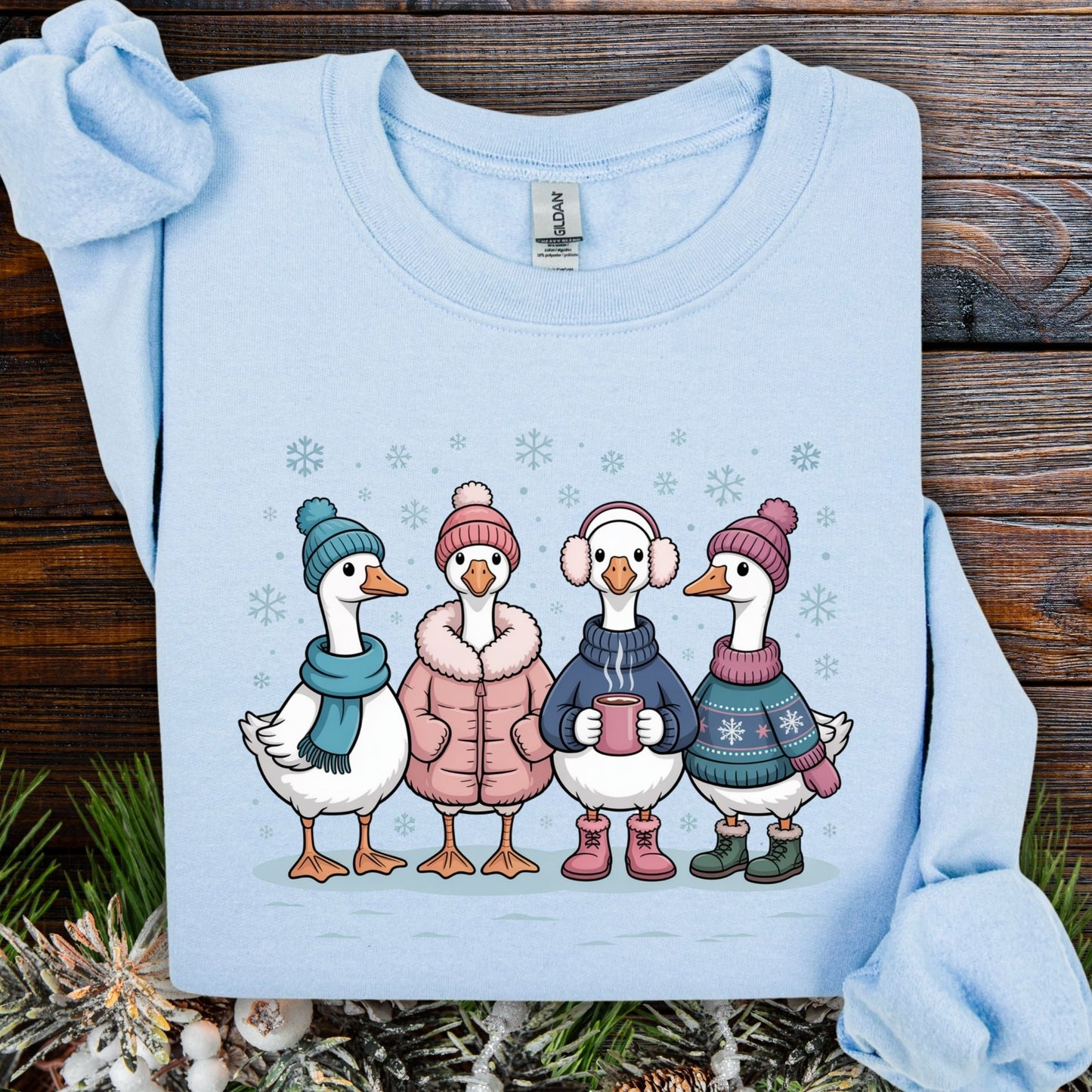 Light blue Gildan sweatshirt with four cartoon geese in winter clothes, drinking hot chocolate in the snow.