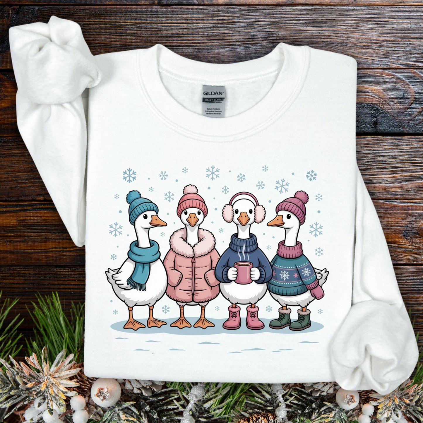 White Gildan sweatshirt with four cartoon geese in winter sweaters, hats, and mittens, drinking hot chocolate.