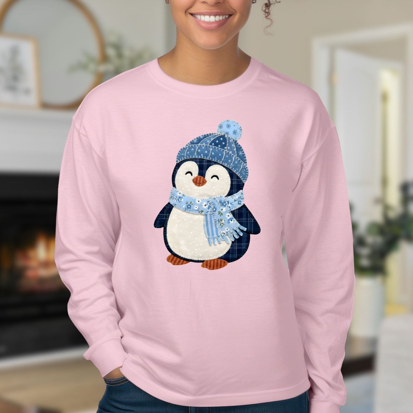 Pink long sleeve tee with a faux patchwork winter penguin wearing a blue hat and scarf.
