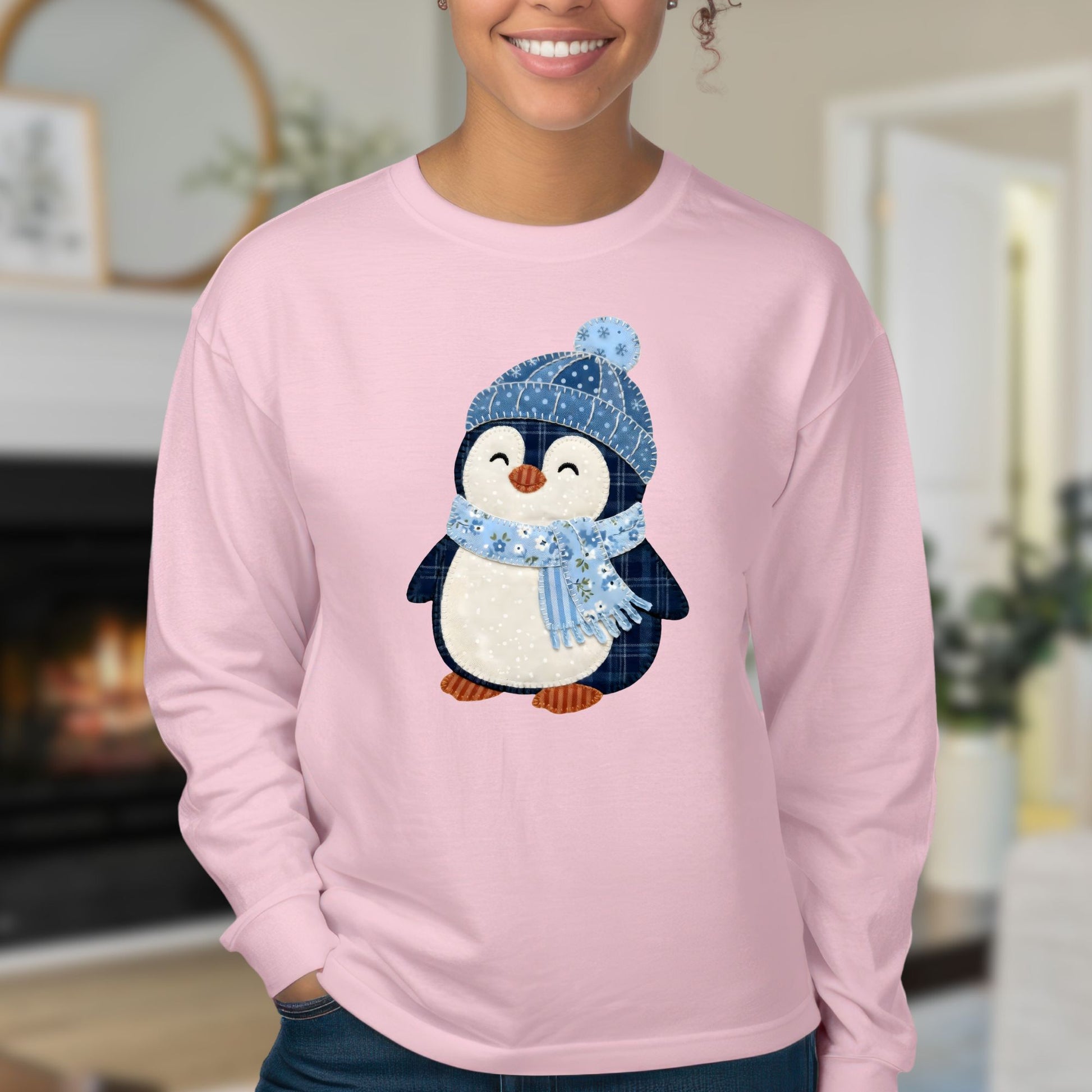 Pink long sleeve tee with a faux patchwork winter penguin wearing a blue hat and scarf.