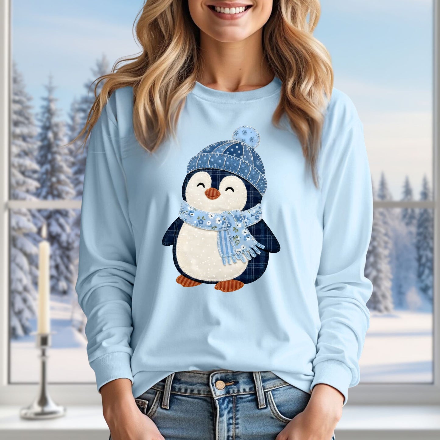 Light blue long sleeve tee with a cute faux patchwork winter penguin in a blue hat and scarf.