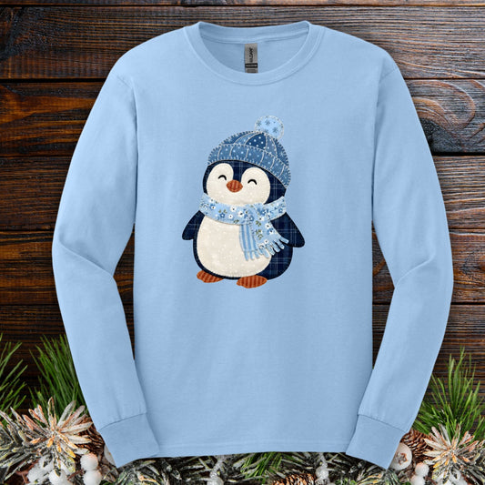 Light blue long sleeve tee with a faux patchwork winter penguin in a blue hat and scarf.