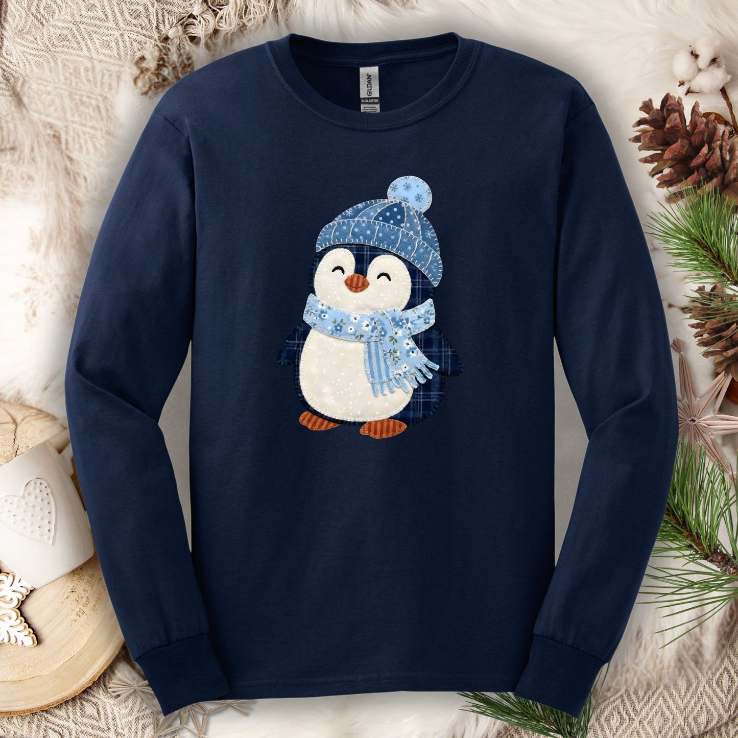 Navy long sleeve tee with a cute faux patchwork winter penguin in a blue hat and scarf.