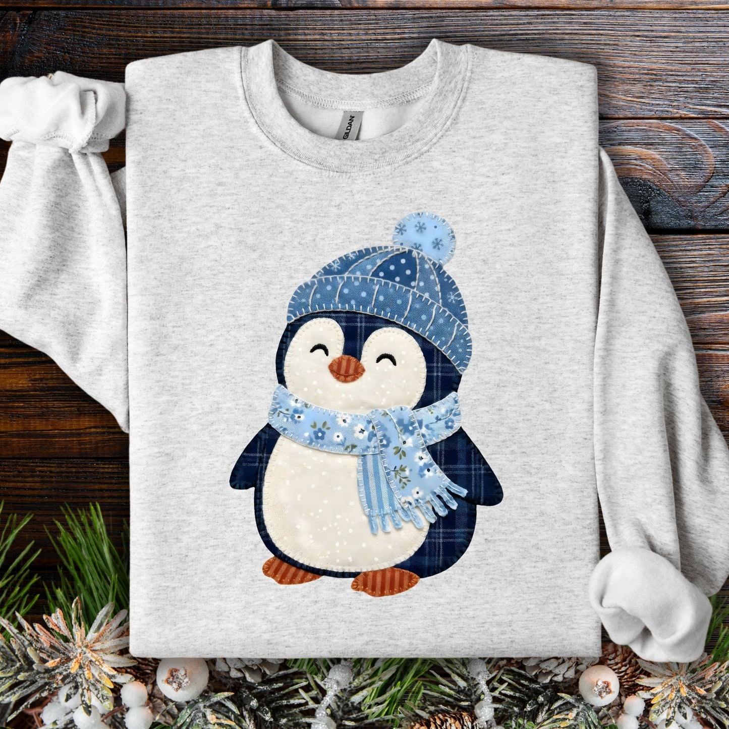 Ash S heavy blend sweatshirt with a cute faux patchwork penguin wearing a blue hat and scarf.
