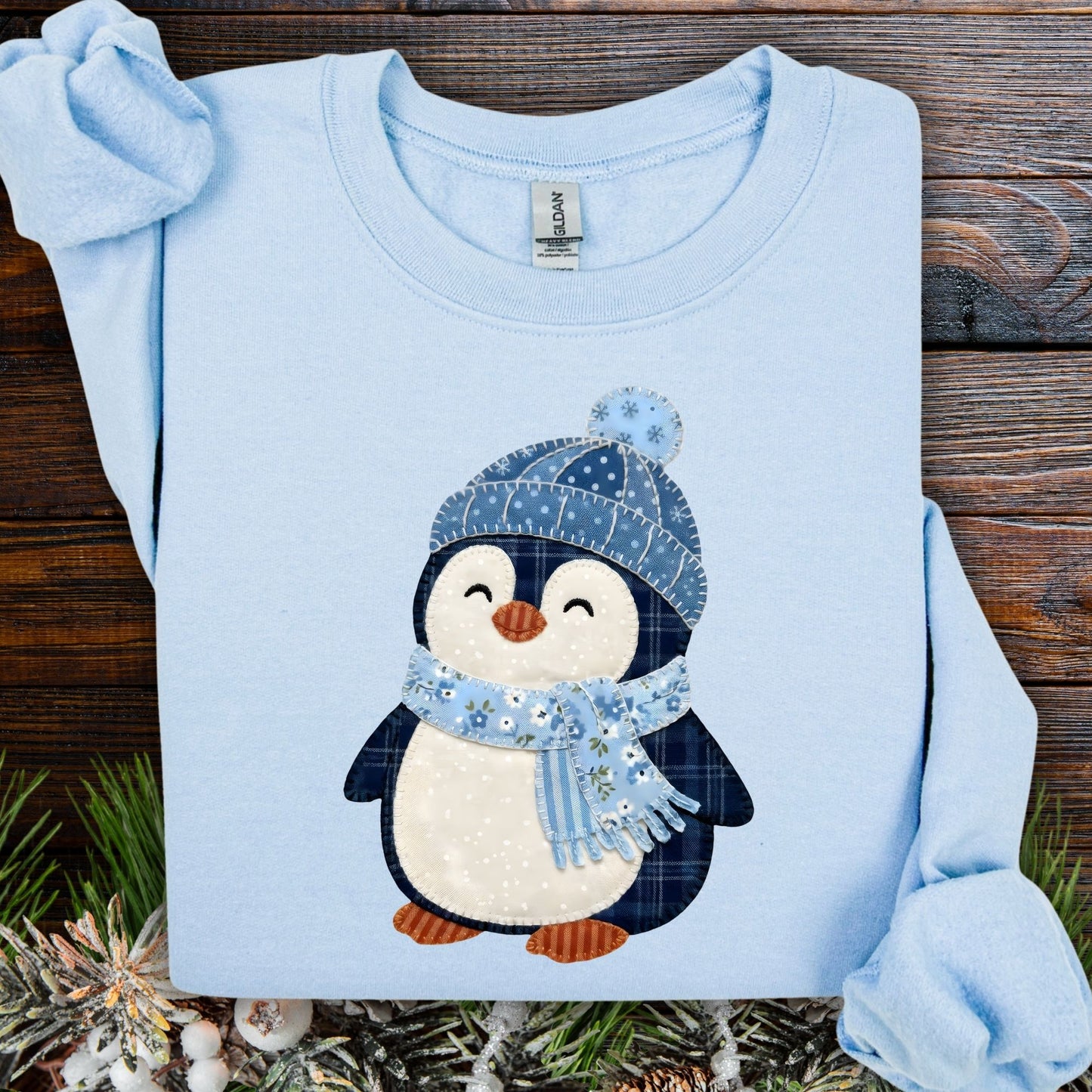 Light blue sweatshirt with a cute faux patchwork penguin wearing a blue hat and scarf.