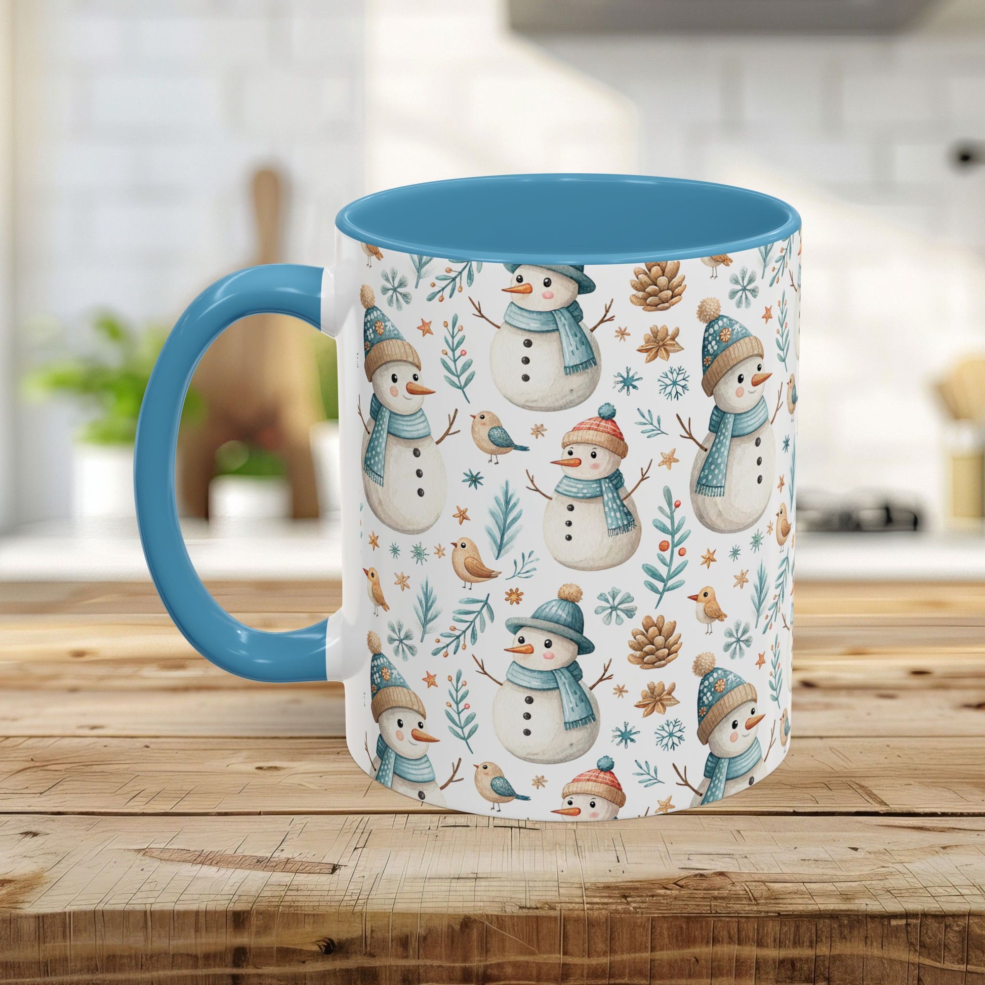 White ceramic mug with watercolor snowmen, birds, and pinecones, featuring a blue handle and interior.