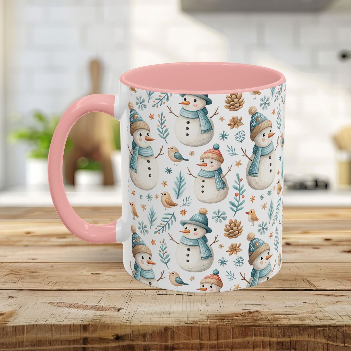 White ceramic mug with pink handle and interior, featuring a watercolor pattern of snowmen, birds, and pinecones.
