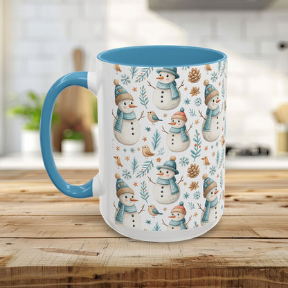 White ceramic 15oz mug with blue interior/handle, featuring a watercolor pattern of snowmen, birds, and pinecones.