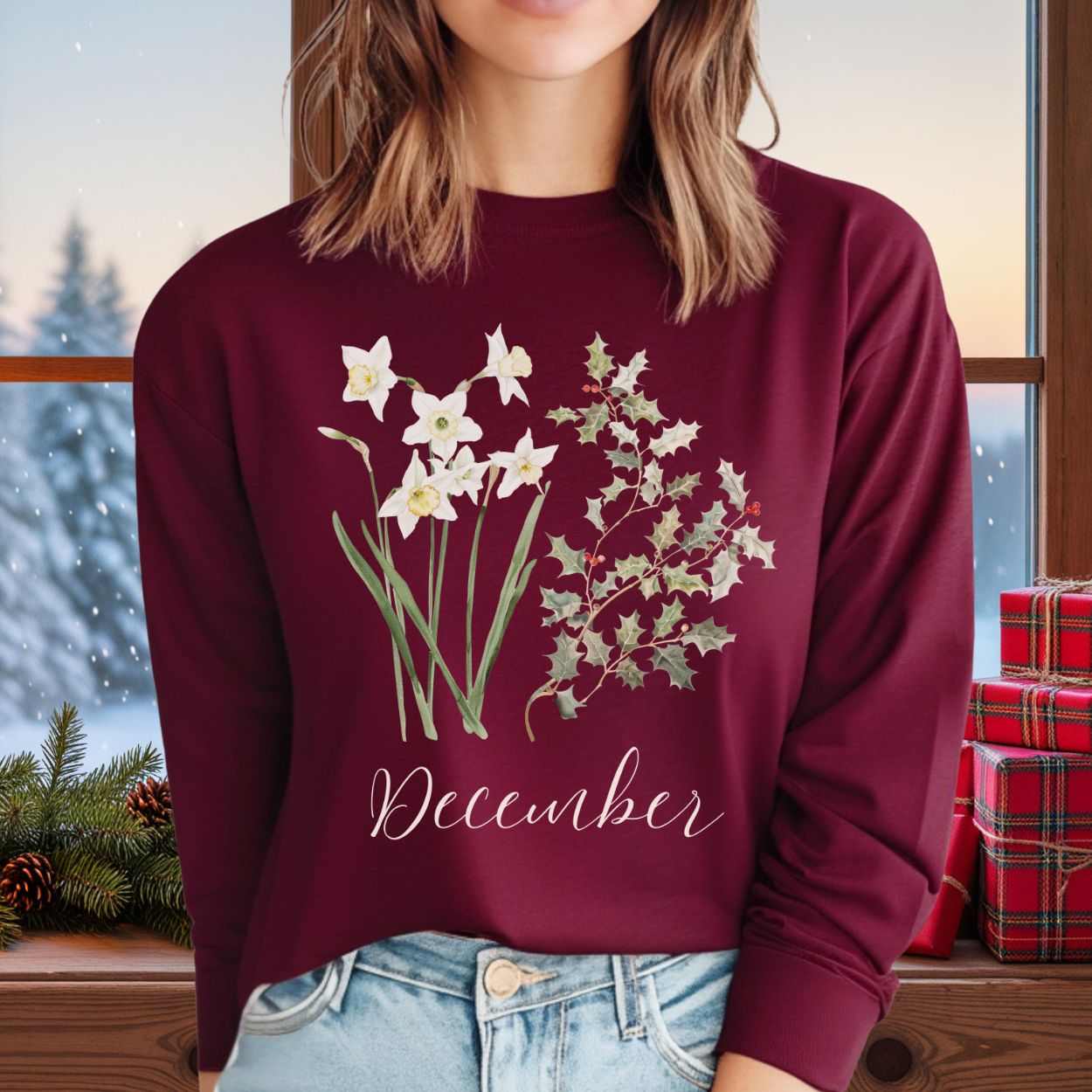 Maroon long-sleeve tee with watercolor narcissus, holly, and "December" script, worn by a person.