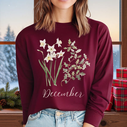 Maroon long-sleeve tee with watercolor narcissus, holly, and "December" script, worn by a person.