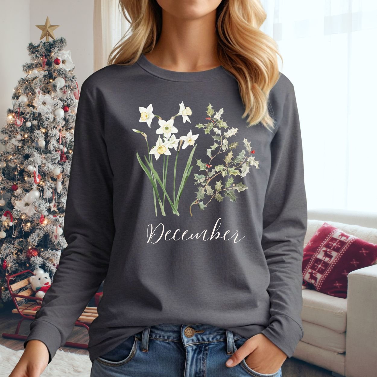 Woman in a charcoal long sleeve tee with watercolor narcissus and holly berry design, "December" script.