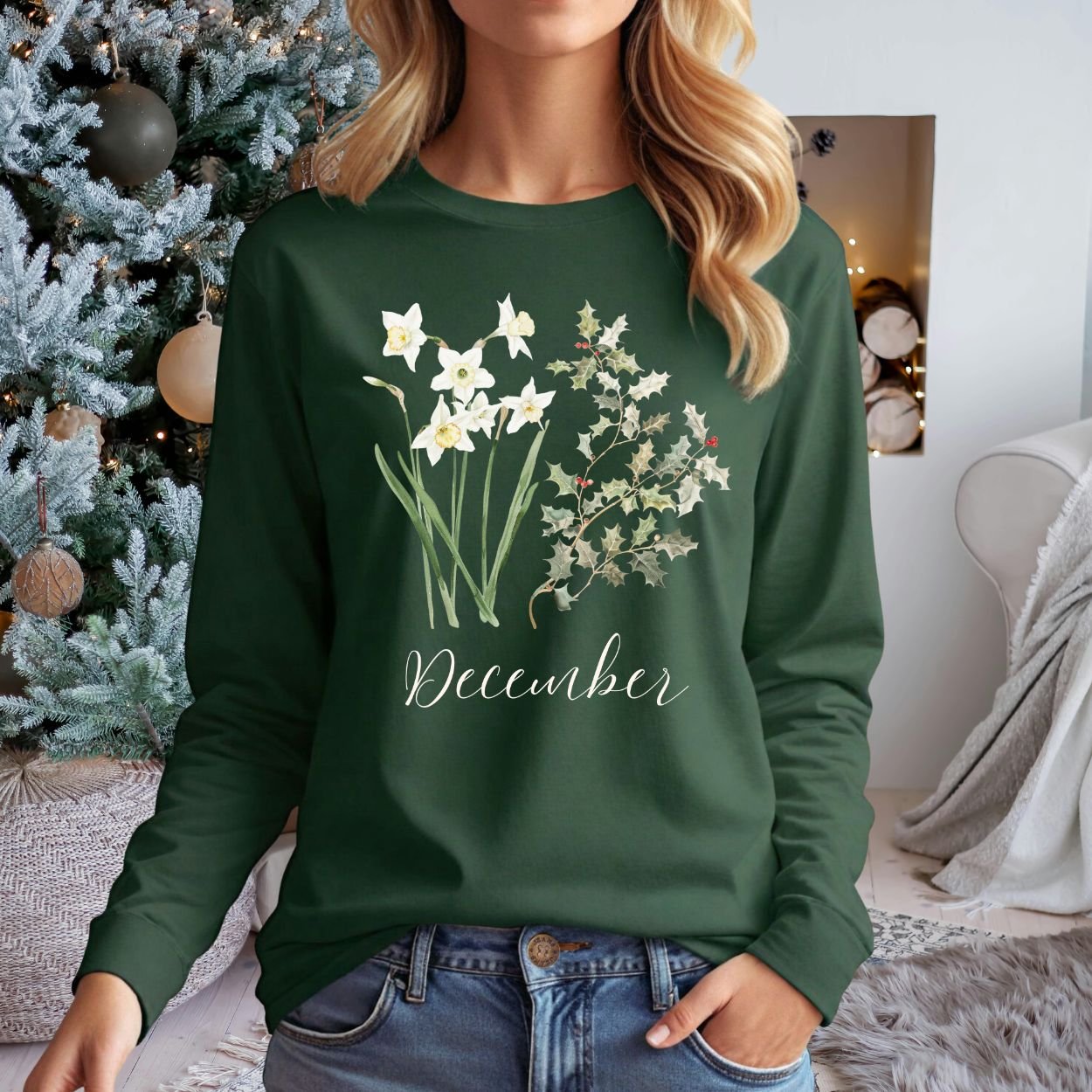 Woman in a dark green long-sleeve tee with watercolor narcissus and holly berry design, "December" script.