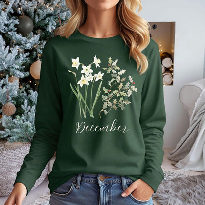 Woman in a dark green long-sleeve tee with watercolor narcissus and holly berry design, "December" script.