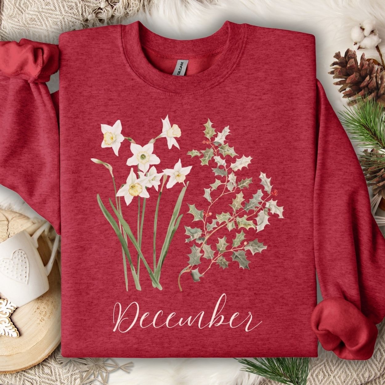 Antique Cherry Red unisex sweatshirt with watercolor narcissus, holly, and "December" text.