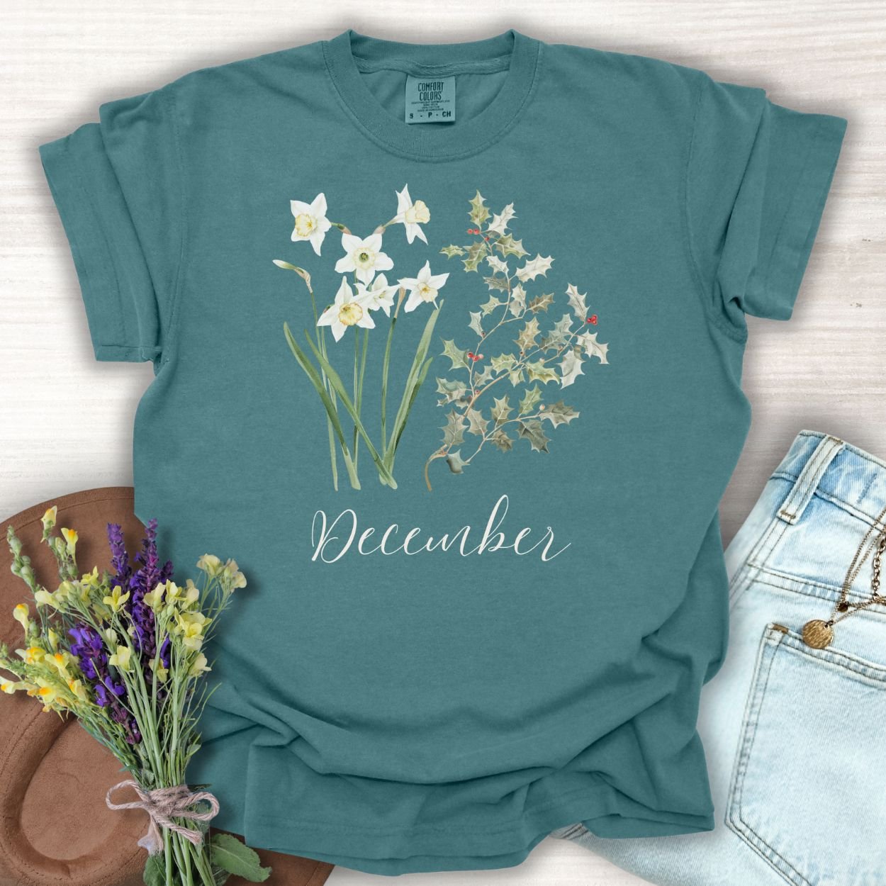 Blue Spruce S-size t-shirt with watercolor narcissus and holly berry design, "December" text.