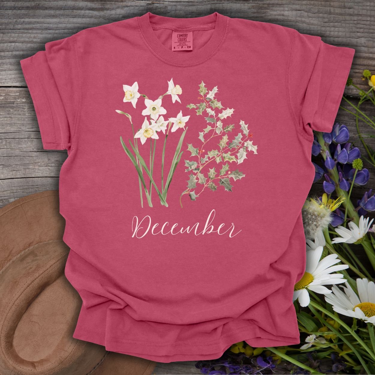 Brick red garment-dyed cotton t-shirt with watercolor narcissus, holly, and "December" script.