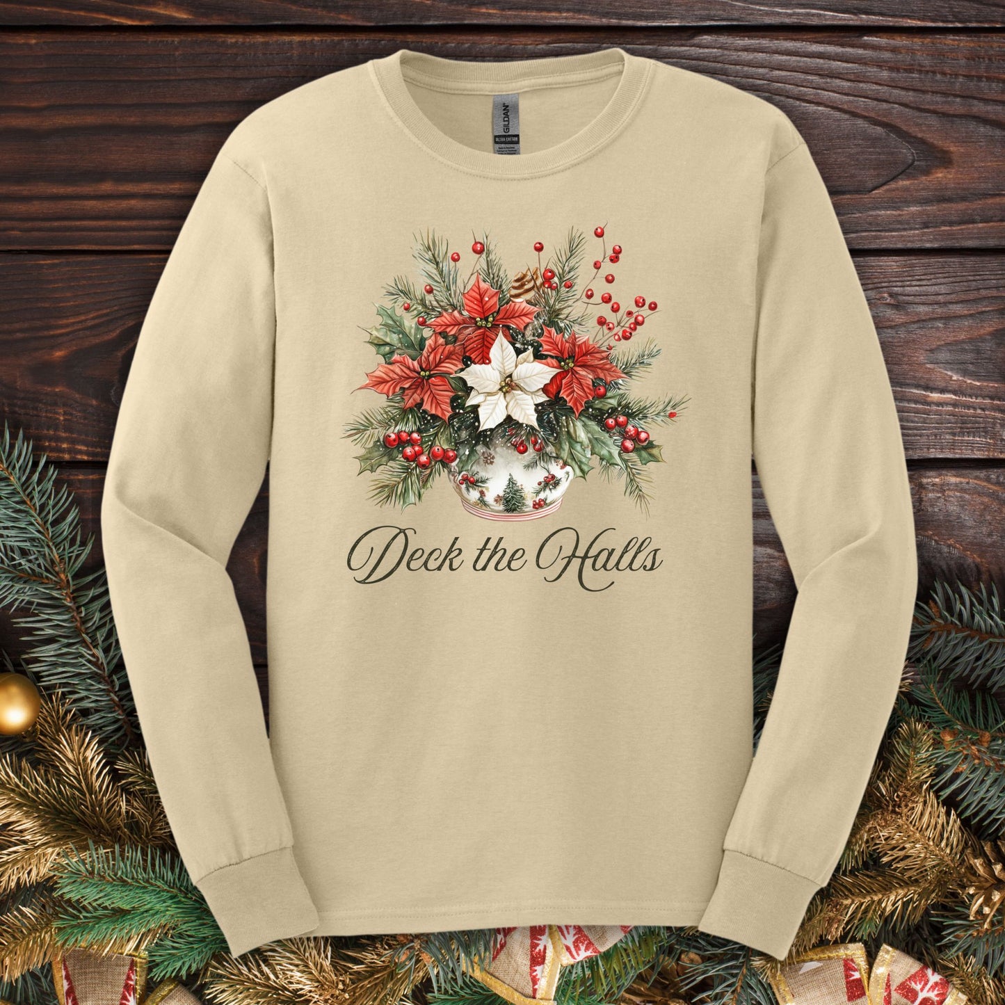 Sand long sleeve tee with watercolor poinsettia arrangement, evergreens, berries, and "Deck the Halls" script.