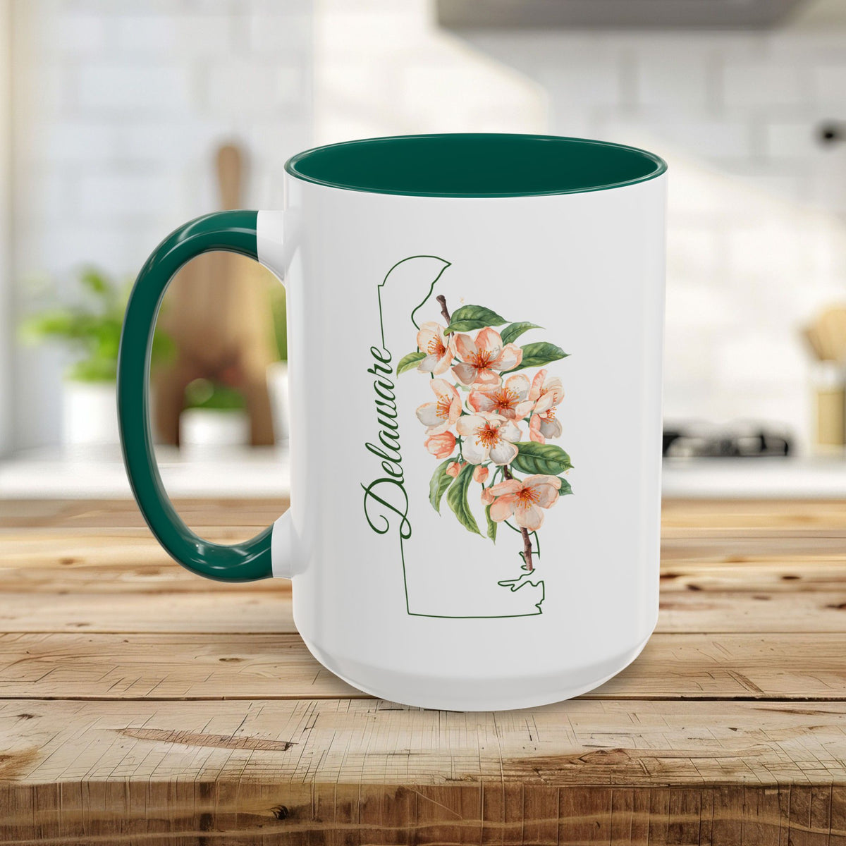White ceramic mug with green handle and interior, featuring a Delaware outline and peach blossom watercolor art.