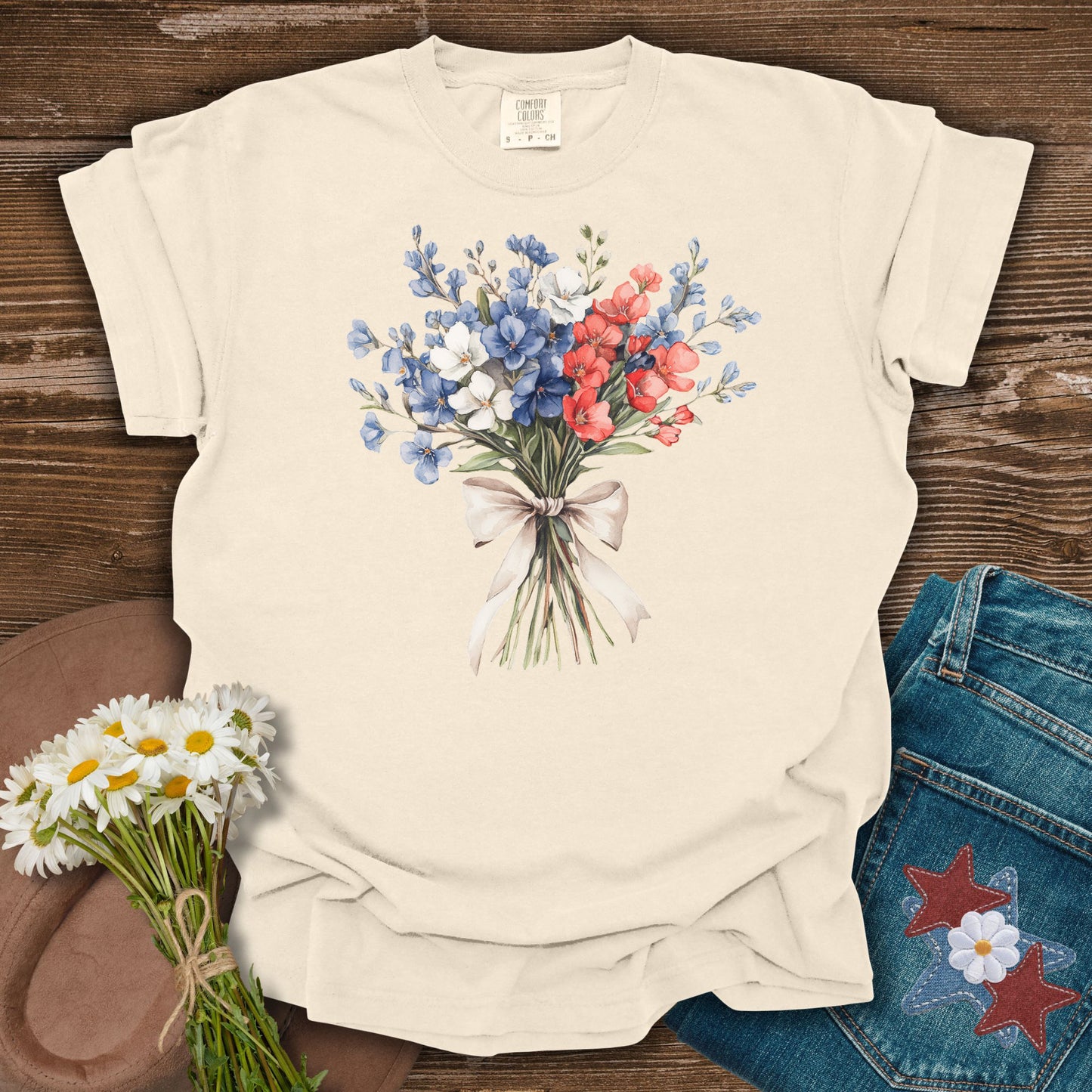 Ivory S t-shirt with a patriotic red, white, and blue floral bouquet and ribbon graphic.