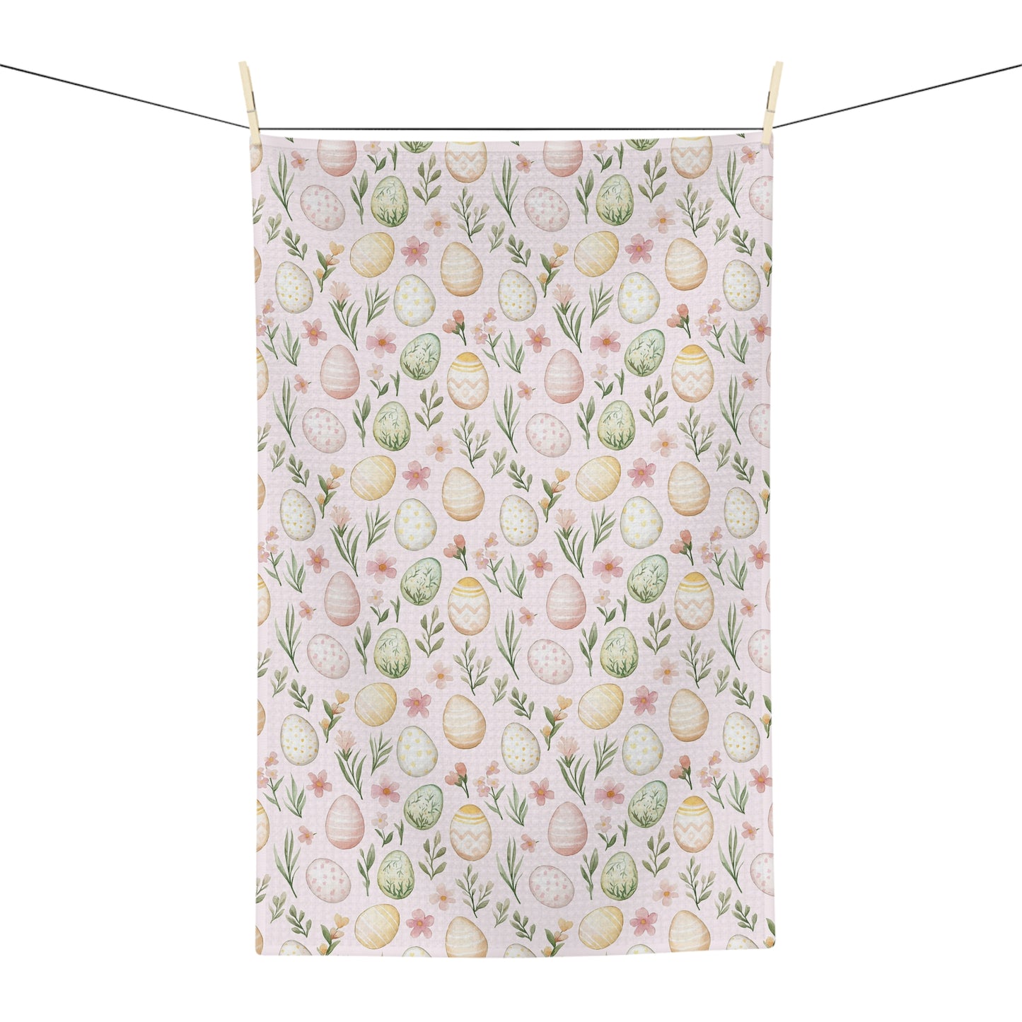 Pastel pink microfiber tea towel with watercolor Easter eggs and spring floral design, hanging from a clothesline.