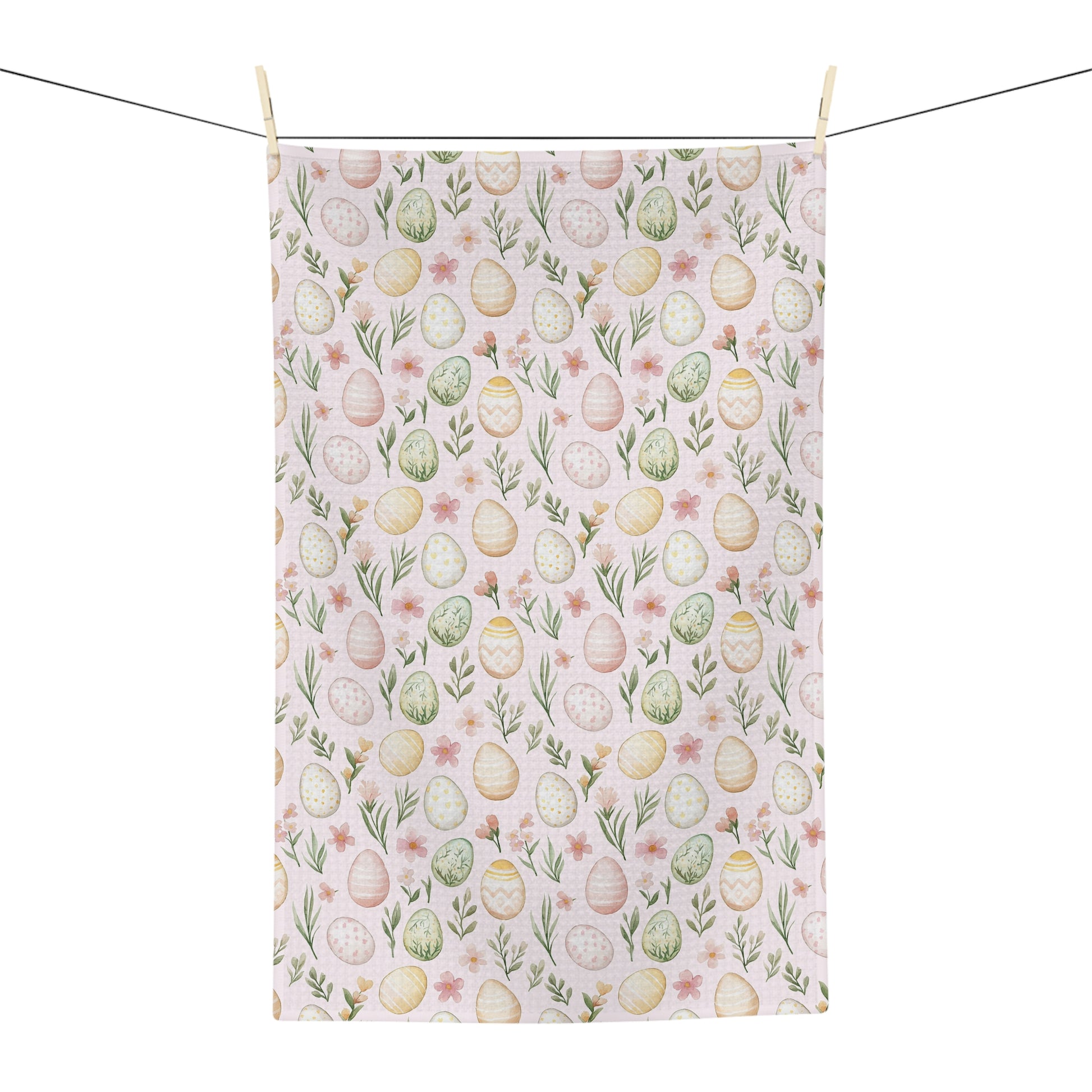 Pastel pink microfiber tea towel with watercolor Easter eggs and spring floral design, hanging from a clothesline.