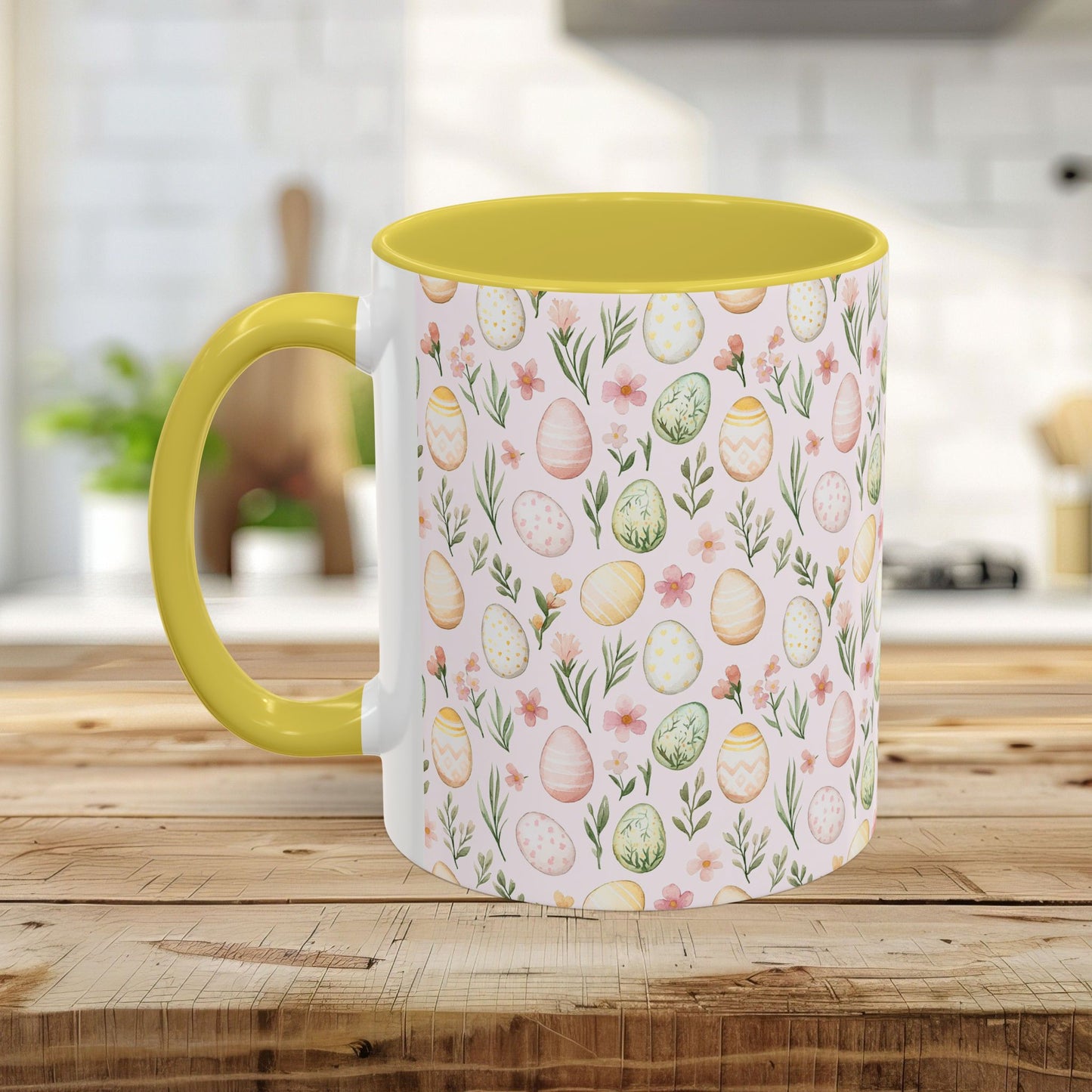Ceramic mug with pastel watercolor Easter eggs & flowers, yellow interior/handle, on a wooden table.