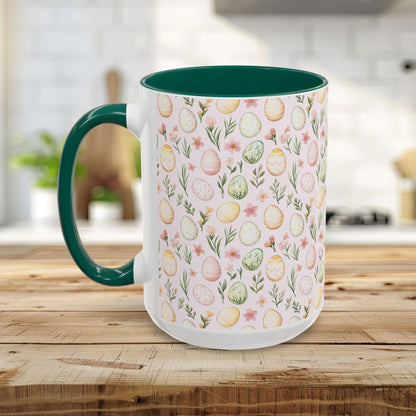 White ceramic mug with pastel watercolor Easter eggs and flowers, green handle and interior, on a wooden table.