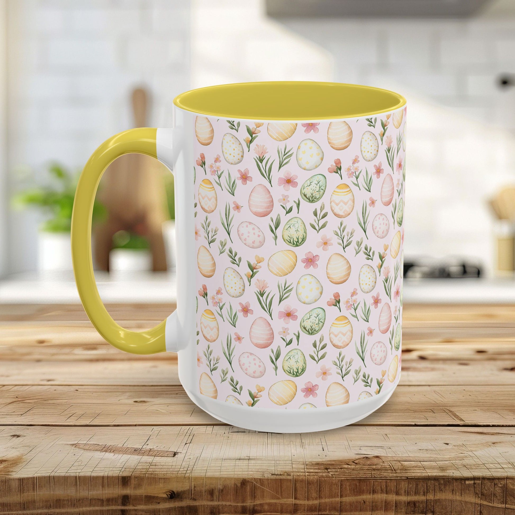 Ceramic mug with pastel watercolor Easter eggs and flowers, yellow handle and interior, on a wooden table.