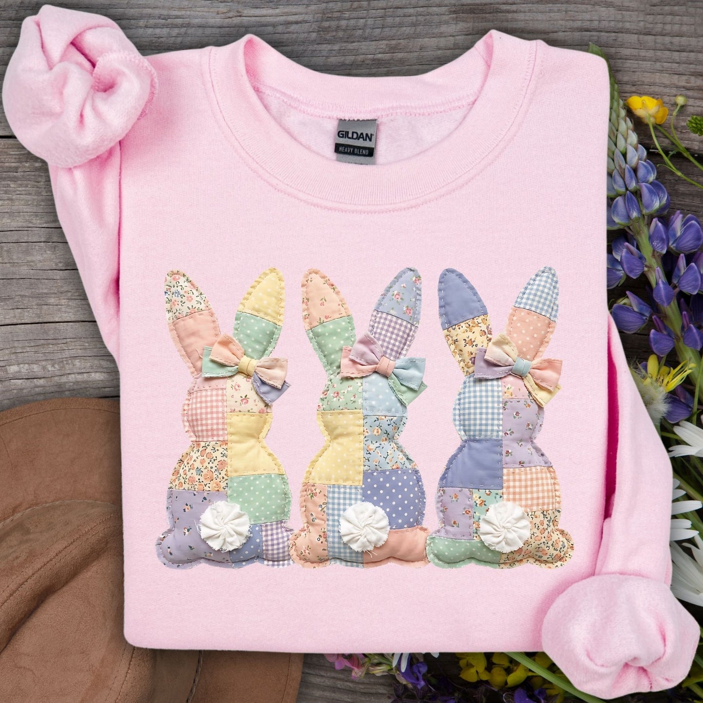 Light pink sweatshirt with three pastel faux patchwork bunnies and white fluffy tails.